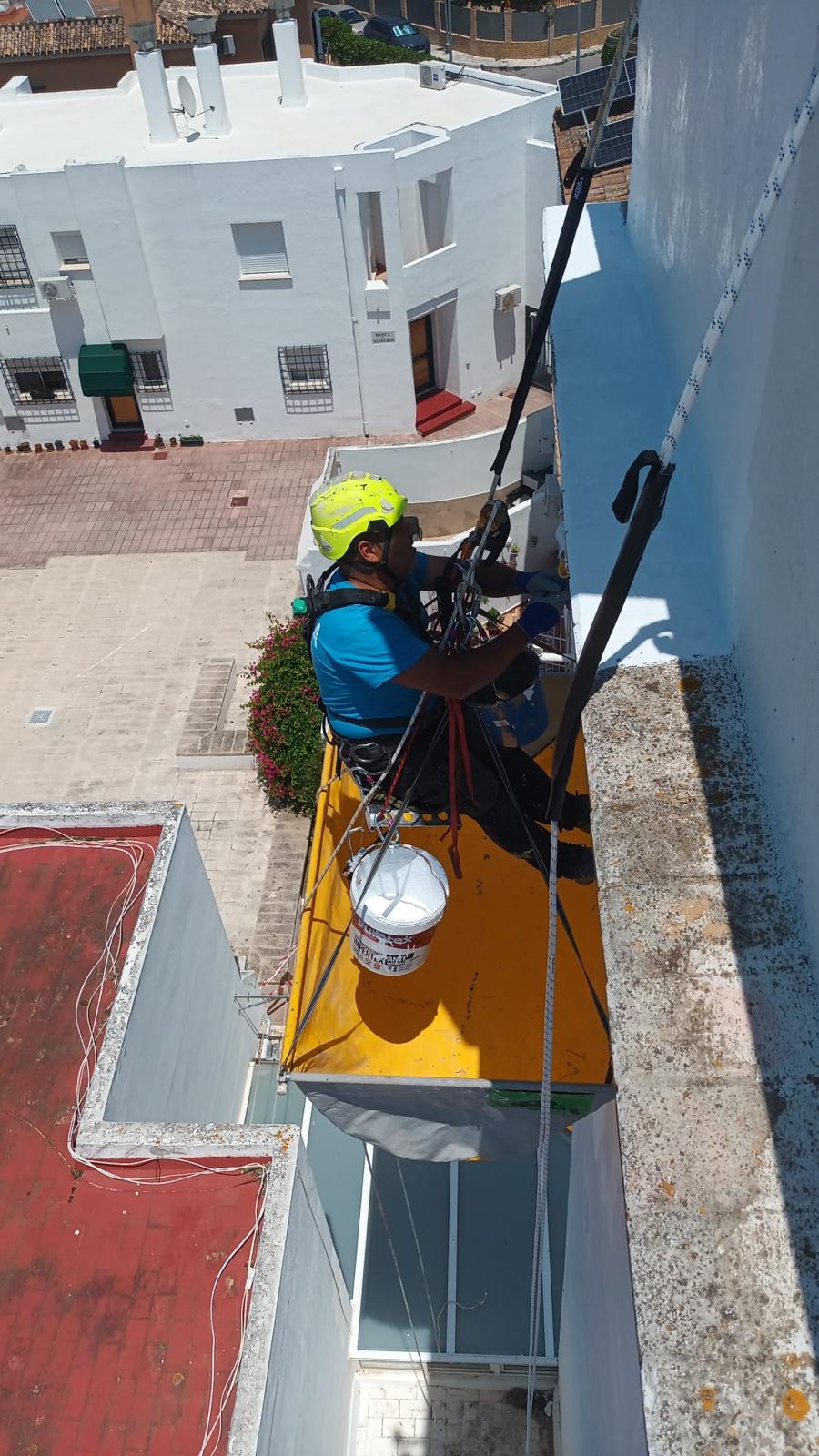 Técnico trabajando desde plataforma suspendida en la fachada de un edificio
