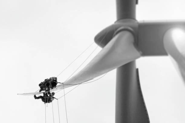 Equipo de técnicos suspendido sobre la pala de un aerogenerador