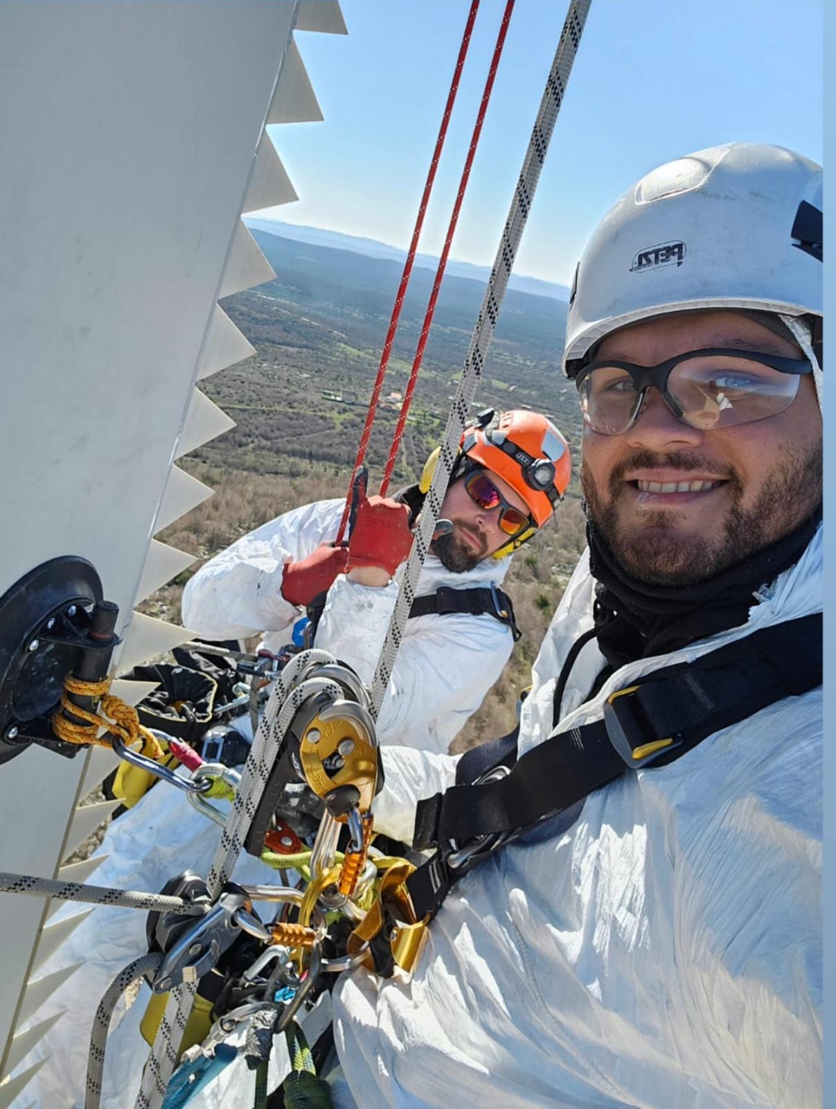 Dos especialistas eólicos trabajando con cuerdas y equipos de protección en altura