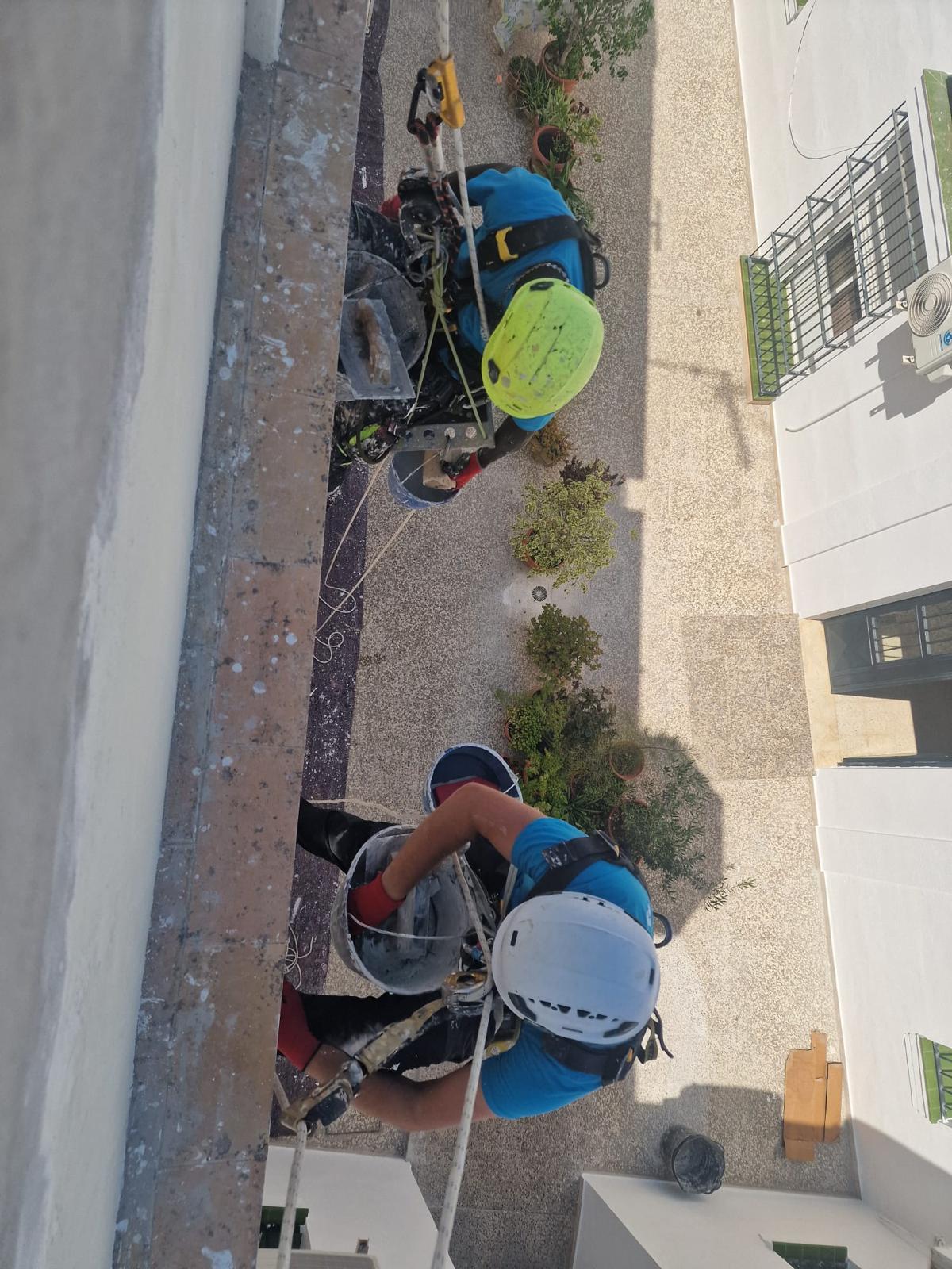Técnicos con arnés y casco preparando la maniobra de descenso en cuerda