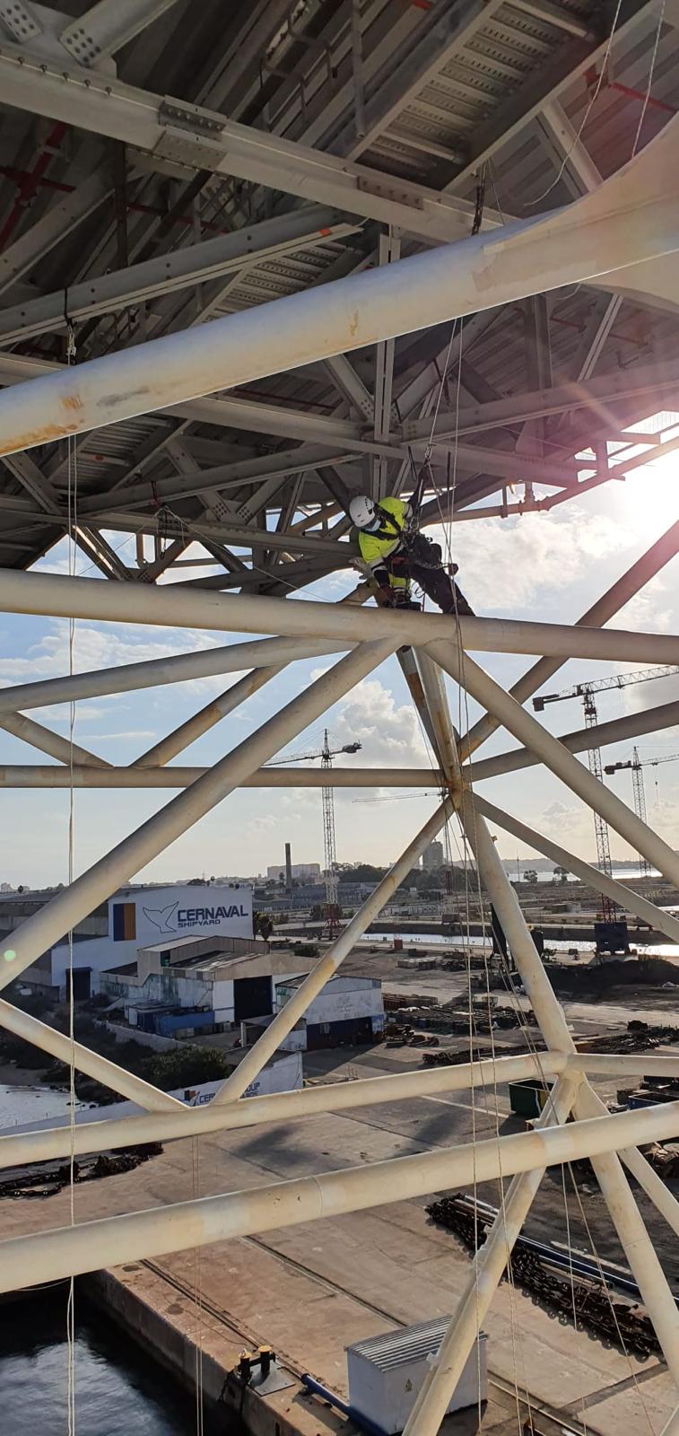 Técnico suspendido entre la estructura metálica de un buque en astillero