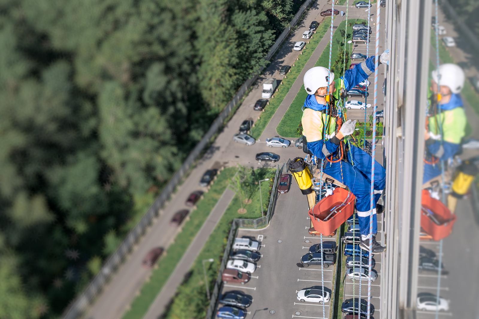 Técnico realizando trabajos verticales suspendido sobre la fachada de un edificio en altura